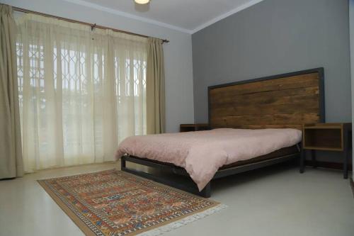 a bedroom with a bed and a rug and a window at Kololo 3BR with Garden, 500m to Acacia Mall in Kampala