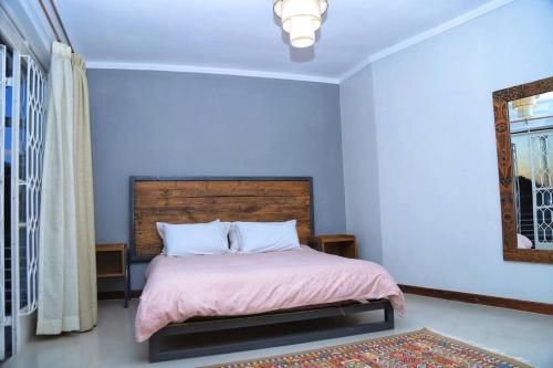 a bedroom with a bed with a pink blanket and a mirror at Kololo 3BR with Garden, 500m to Acacia Mall in Kampala