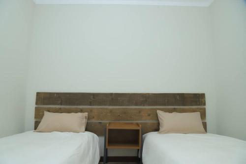 two beds with white sheets and a table between them at Kololo 3BR with Garden, 500m to Acacia Mall in Kampala