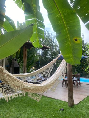 a hammock on a patio with chairs and a pool at Casa Hibiscus Beach Club Ipioca Maceió in Maceió