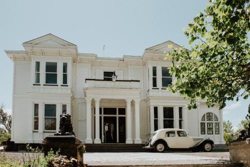 ein altes Auto, das vor einem weißen Haus parkt in der Unterkunft Mt Vernon Villa in  Waipukurau