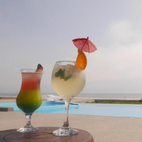 two cocktails sitting on a table next to a pool at Darenas Hacienda in Aucallama