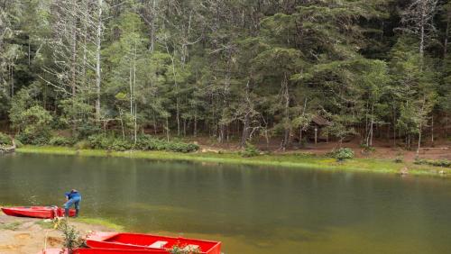 a man standing in the water next to a red boat at Hacienda La Lucha in Lucha