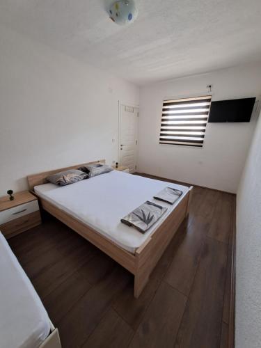 a white bedroom with a large bed and a window at Lazarov Apartments in Nov Dojran