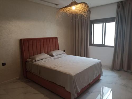 um quarto com uma cama grande e um lustre em Appartement luxueux proche de tout em Fez