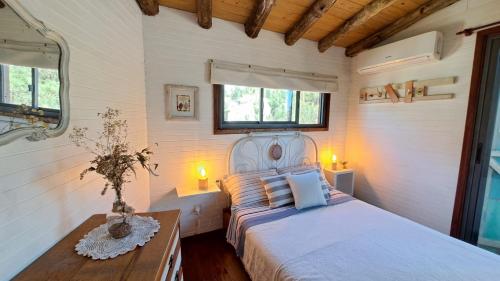 a bedroom with a bed and a table and two windows at Cabañas Bahia Serena in Punta Del Diablo