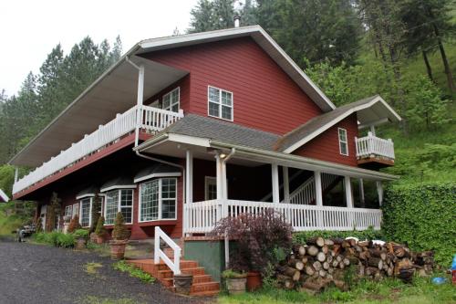 ein rotes Haus mit einer weißen Veranda in der Unterkunft Hearthstone Elegant Lodge in Kamiah