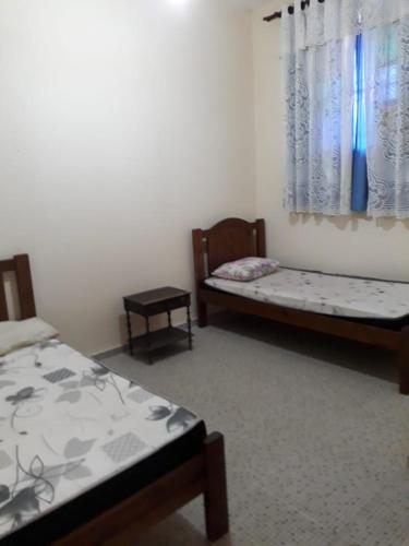 a room with two beds and a window at Casa do Edi in Maricá