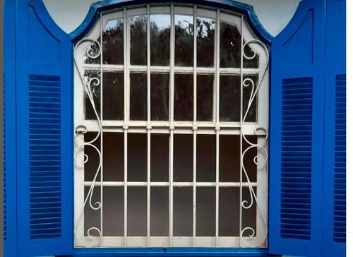 una ventana azul con barras en un edificio en O Casarão en Passa Quatro