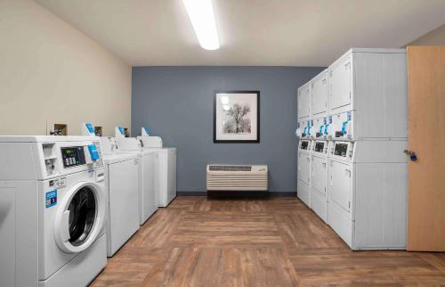a laundry room with white washing machines and a blue wall at Extended Stay America Select Suites - New Orleans - Airport in Kenner