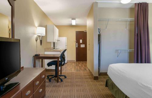a hotel room with a bed and a desk with a computer at Extended Stay America Suites - Detroit - Metropolitan Airport in Romulus