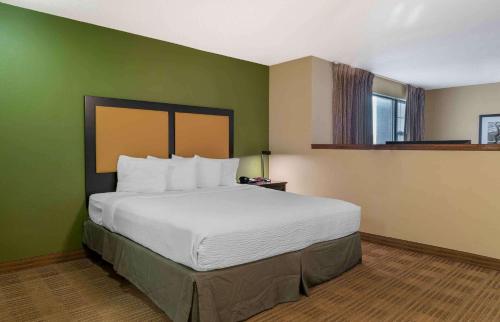 a large bed in a room with a green wall at Extended Stay America Suites - Detroit - Metropolitan Airport in Romulus