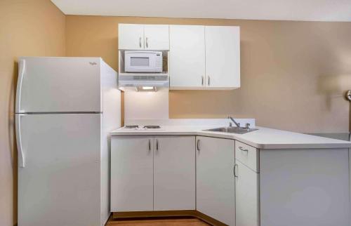 a kitchen with white cabinets and a white refrigerator at Extended Stay America Suites - San Jose - Edenvale - North in San Jose