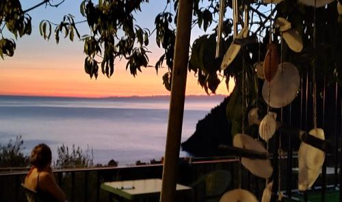 een vrouw die uitkijkt op de oceaan bij zonsondergang bij Perla del Levante Hostel in Framura