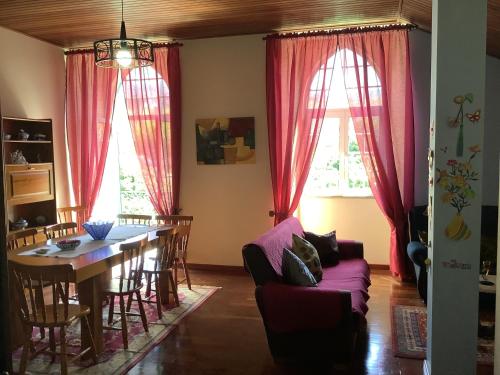 ein Wohnzimmer mit einem Esstisch und roten Vorhängen in der Unterkunft Casa das Camélias in Gouveia