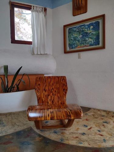 a wooden chair in a room with a bed at El Encinal de las Flores in Valle de Bravo