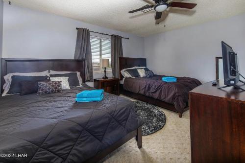 a bedroom with two beds and a flat screen tv at Horror House- arcade & heated pool! Room for all! in Lake Havasu City