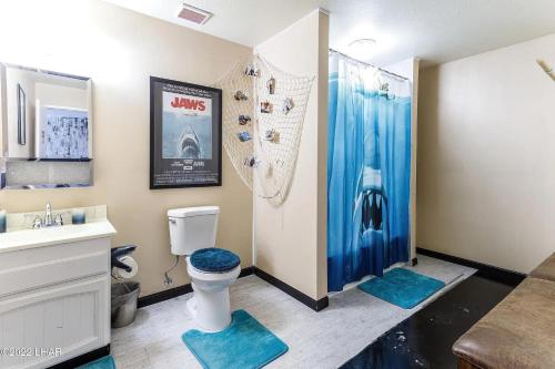 baño con aseo y ducha con alfombras azules en Horror House- arcade & heated pool! Room for all! en Lake Havasu City