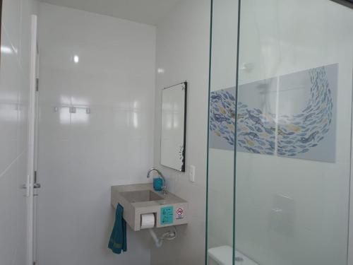 een badkamer met een wastafel en een glazen douche bij Sobrado Carpe Diem Palmeiras, 450 m da praia, 2 suítes com ar, 2 vagas, check-in 24h, churrasqueira, 20 min do Beto Carrero in Piçarras