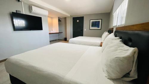 a hotel room with two beds and a flat screen tv at HIT Merida Hotel Boutique in M&eacute;rida