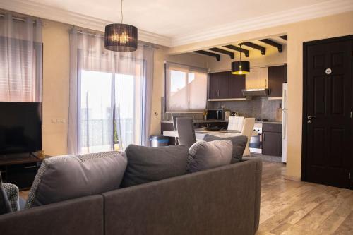 uma sala de estar com um sofá e uma cozinha em Magnifiaue appart em Marrakech