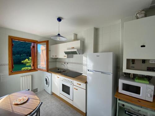 a kitchen with a table and a white refrigerator at BUENAVISTA2 in Biescas