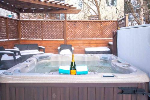 a hot tub with a bottle of wine in it at Chalet BIA - Le Petit Chaleureux in Ham Nord