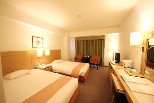 a hotel room with two beds and a desk at Chateraise Gateaux Kingdom Sapporo Hotel & Spa Resort in Sapporo