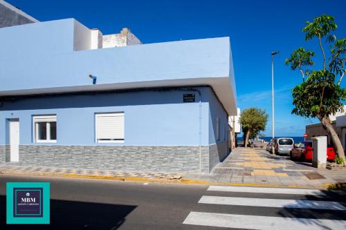 a white building on a street with a parking lot at Mara 2 Playa del Burrero junto al mar, wifi gratis in Ingenio