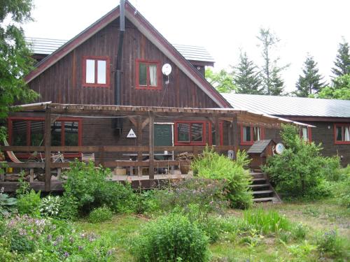 a large wooden house with stairs in front of it at Toipirka Kitaobihiro Youth Hostel in Otofuke