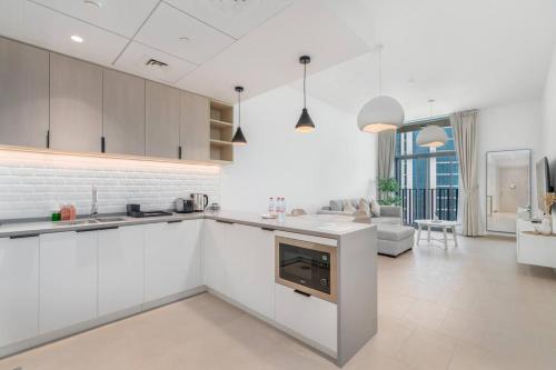 a kitchen with white cabinets and a living room at 1bdr in Belgravia Heights - JVC - Dubai in Dubai