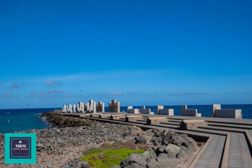 a walkway leading to the ocean with buildings in the background at Mara 2 Playa del Burrero junto al mar, wifi gratis in Ingenio