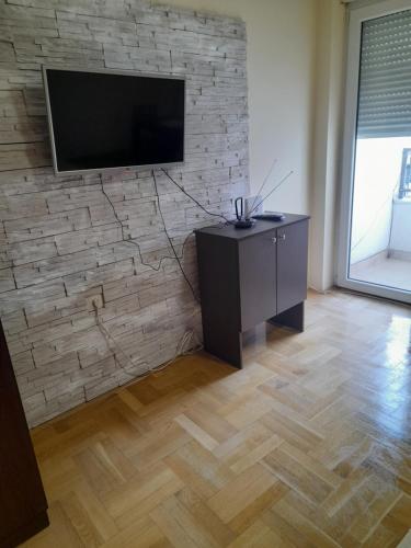 un soggiorno con una TV su un muro di mattoni di For you apartman a Niš