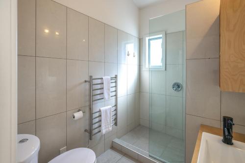 a bathroom with a shower and a toilet and a sink at Paradise on Palm - Stay Waiheke in Palm Beach