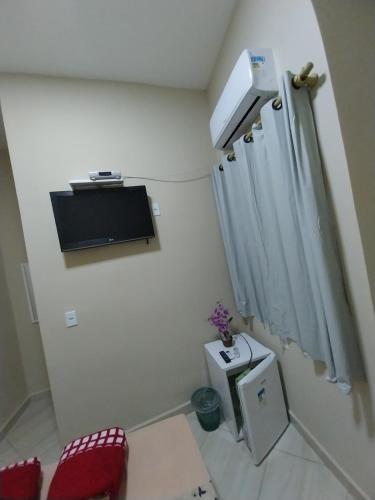 a small white room with a curtain and a tv at Aparecida Akuto's Pousada in Aparecida