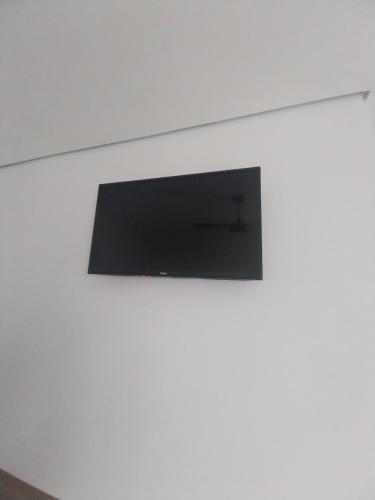 a flat screen tv on a white wall at Aparecida Akuto's Pousada in Aparecida