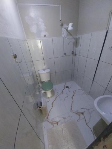 a cracked bathroom with a toilet and a sink at Aparecida Akuto's Pousada in Aparecida