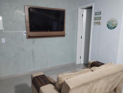 ein Wohnzimmer mit einem Sofa und einem Flachbild-TV in der Unterkunft Casa nova com 3 quartos, equipada com Ar Condicionado, TV, Internet e Área de Lazer Completa - Boiçucanga in Boicucanga