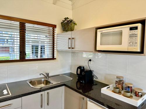 a kitchen with a sink and a microwave at Emerald Inn on Takapuna Beach in Auckland