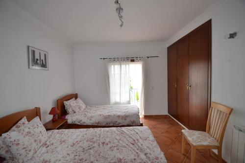 a bedroom with two beds and a cabinet and a window at villa Lagoa in Óbidos