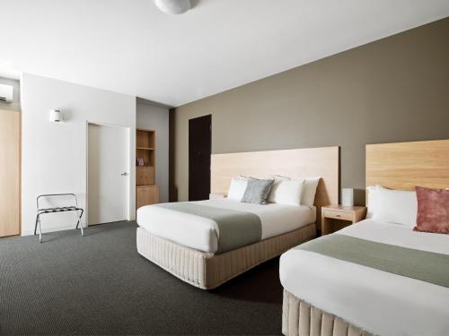 a hotel room with two beds and a chair at Saint Kilda Beach Hotel - formerly Rydges St Kilda in Melbourne