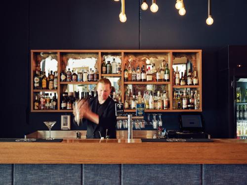 a man standing behind a bar with a bartender at Saint Kilda Beach Hotel - formerly Rydges St Kilda in Melbourne