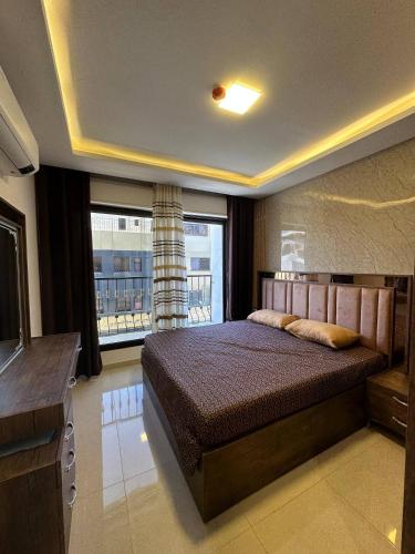 a bedroom with a bed and a large window at Modern 2bedroom For Rent Abdoun in Amman