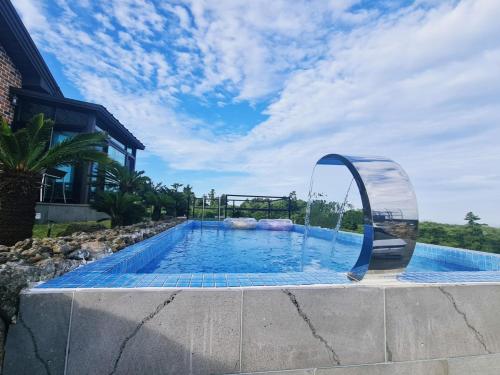 a swimming pool with a water fountain in a yard at Sunshine Aewol Entire House in Jeju