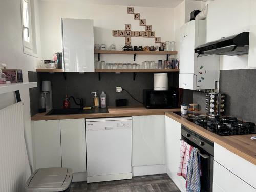 une cuisine avec des armoires blanches et un four à plaques de cuisson dans l'établissement Appartement 4 personnes proche d’un Circuit 24h du Mans, au Mans