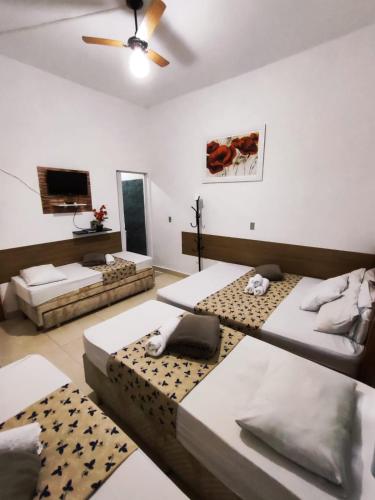 a room with three beds and a flat screen tv at Aparecida Akuto's Pousada in Aparecida