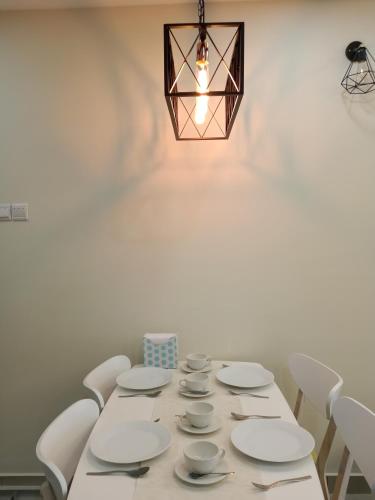 a dining room table with white dishes and a chandelier at LUXURY STAY - 2 ROOMS with CONDO Facility - Mount Austin JB - SPECIAL OFFER in Johor Bahru