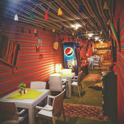 a restaurant with tables and chairs and a red wall at Majido Hotel in Wadi Musa