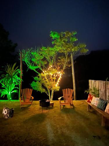 a group of chairs and a tree with lights at Camacica pousada in Miracatu