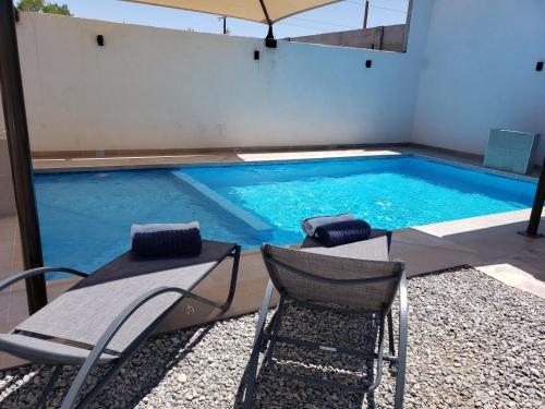 - une piscine avec 2 chaises et un parasol dans l'établissement Casa Olmos, à San Felipe